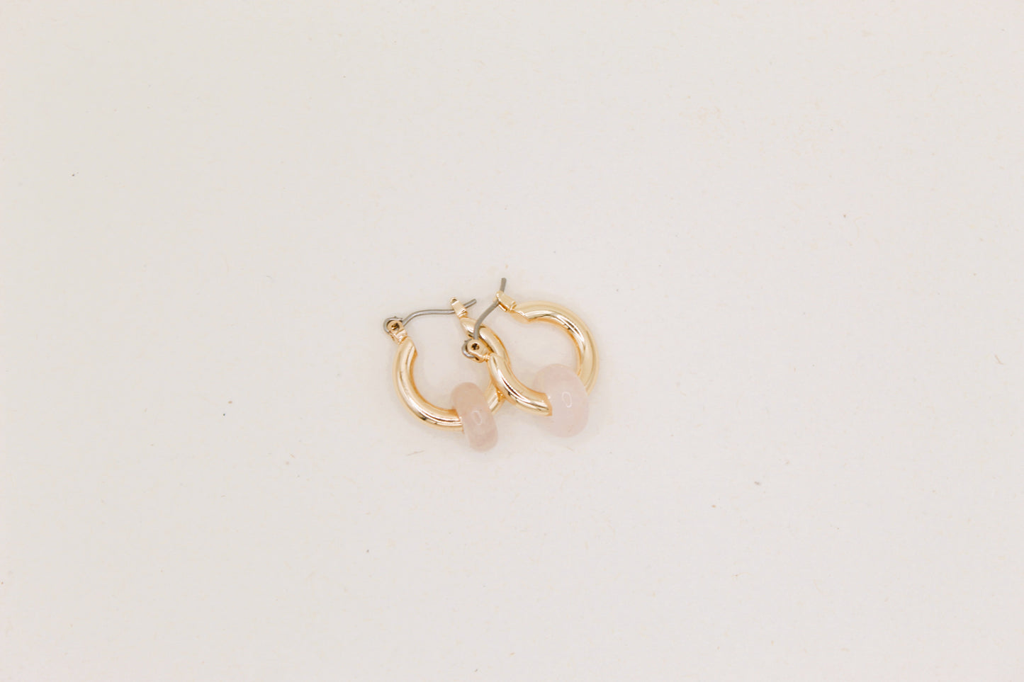 Gold hoop earrings on a light beige background