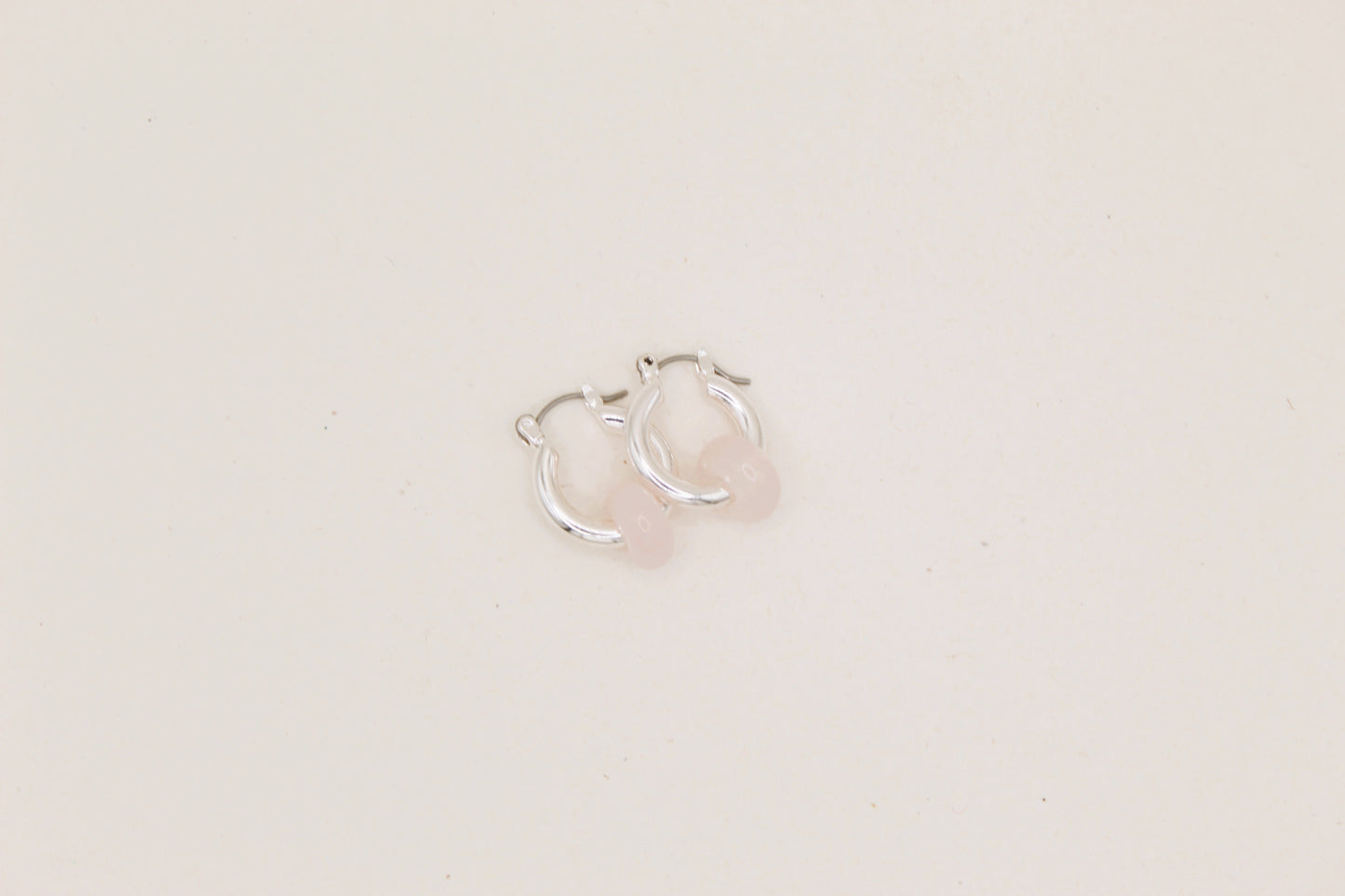 Silver hoop earrings on a light beige background