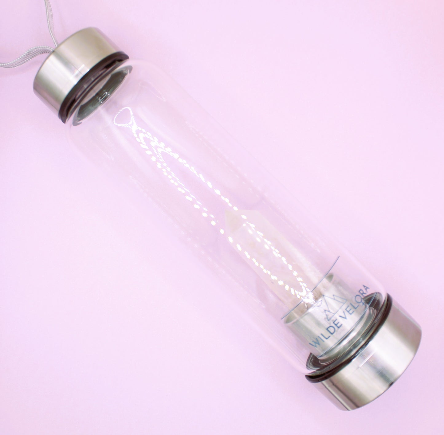 Clear glass bottle with silver cap on a pink background
