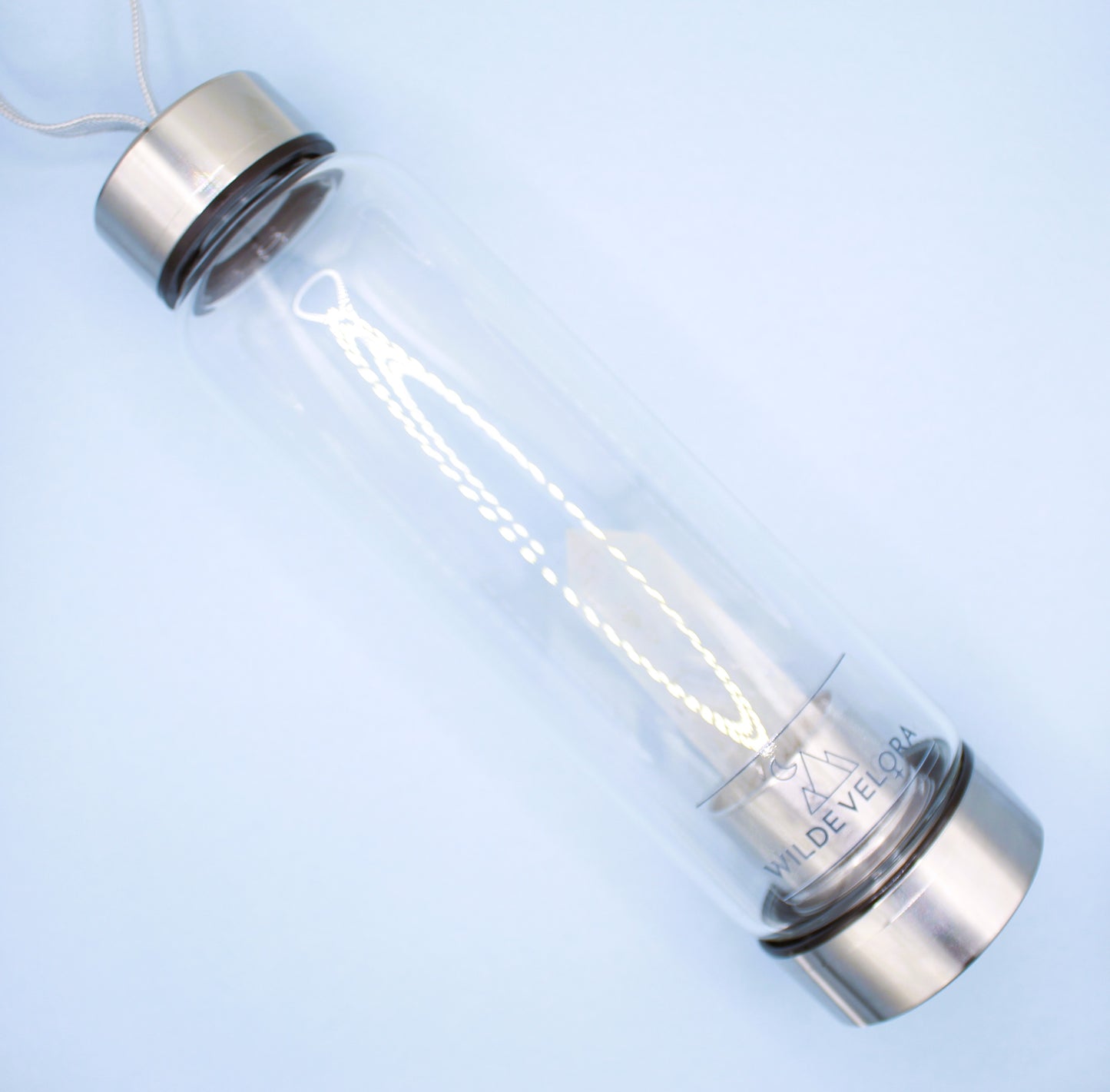 Clear bottle with metal cap and base on a light blue background