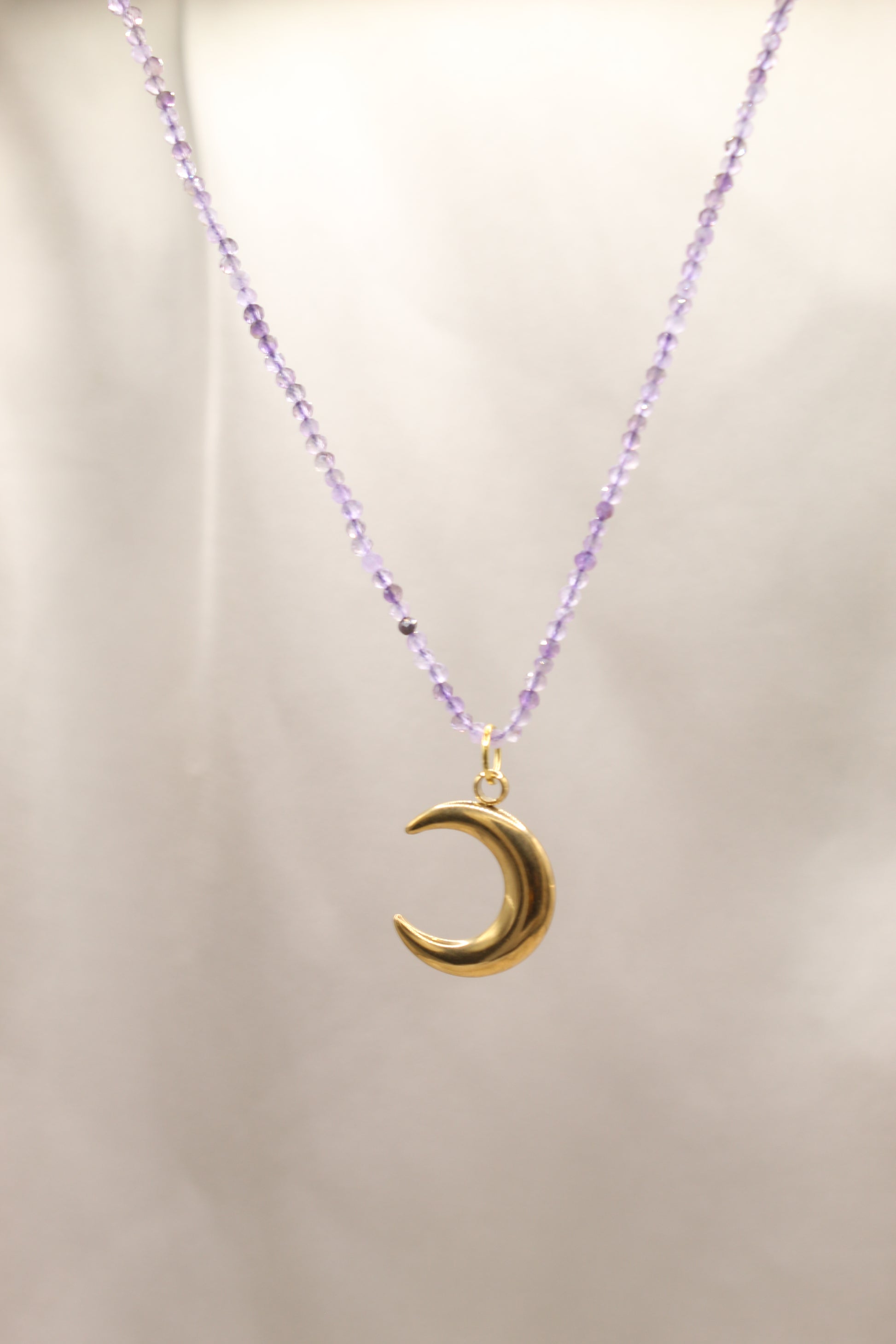Necklace with a gold crescent moon pendant on a light background
