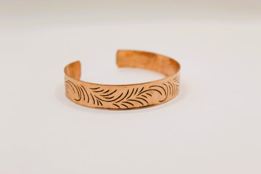 Copper bracelet with leaf patterns on a white background