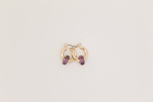 Gold hoop earrings with amethyst stones on a light background