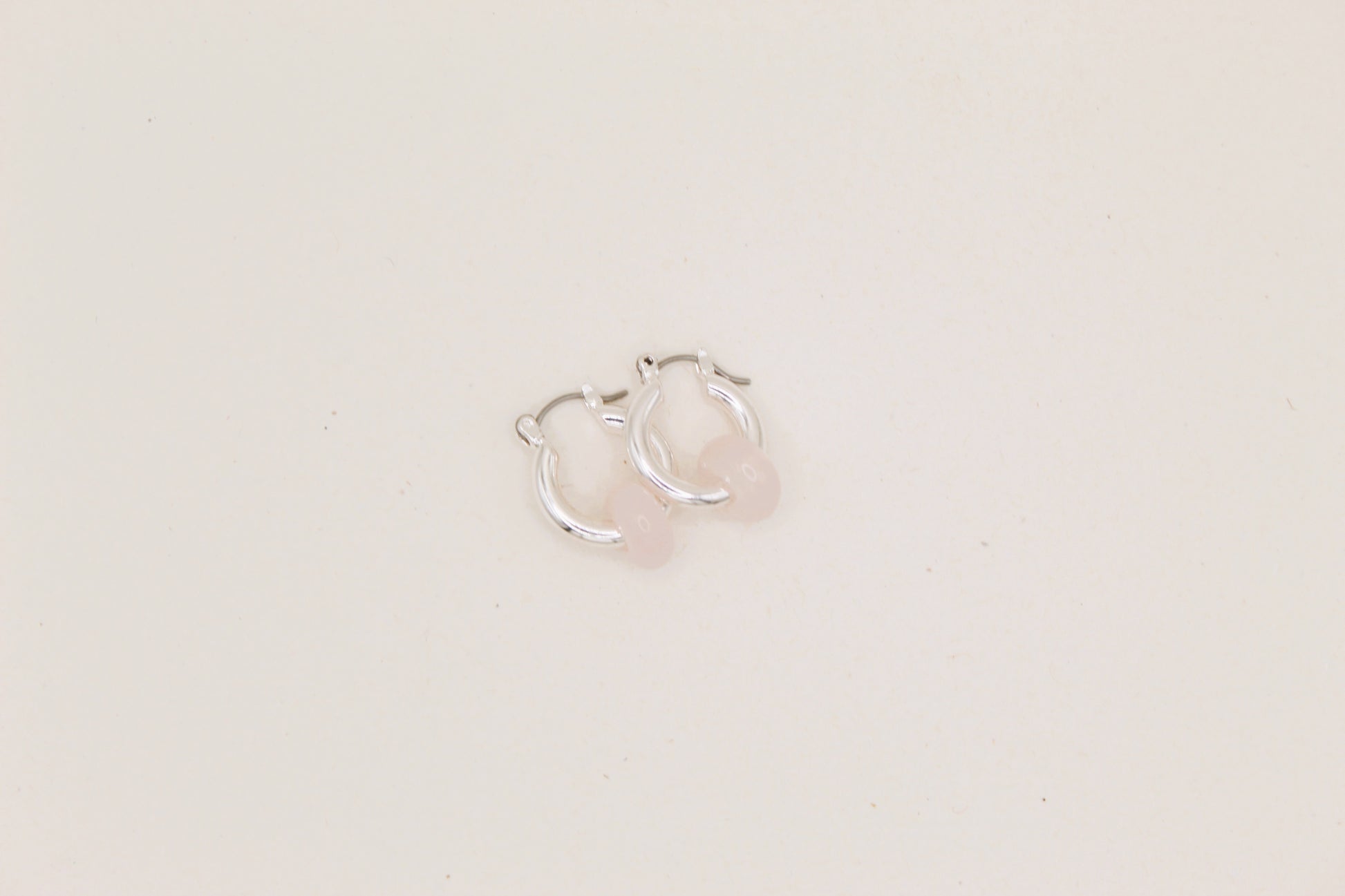 Silver hoop earrings on a light beige background