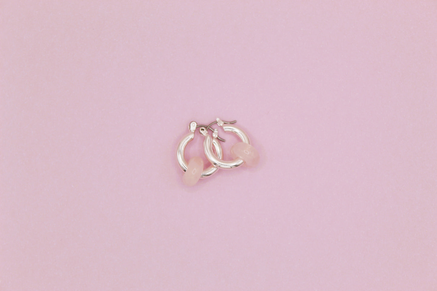 Small silver hoop earrings on a pink background
