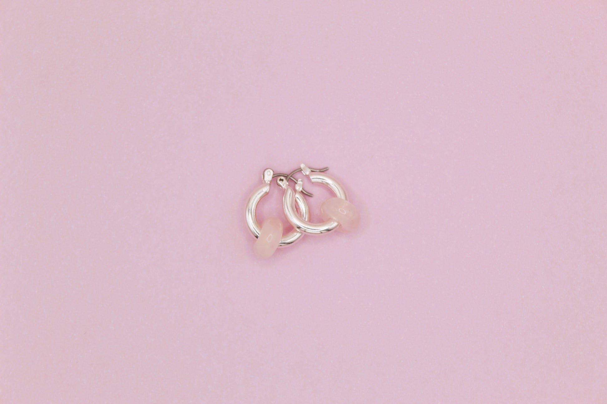 Small silver hoop earrings on a pink background