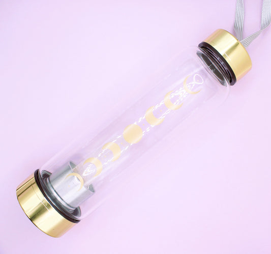 glass bottle with clear quartz crystal and gold top and base