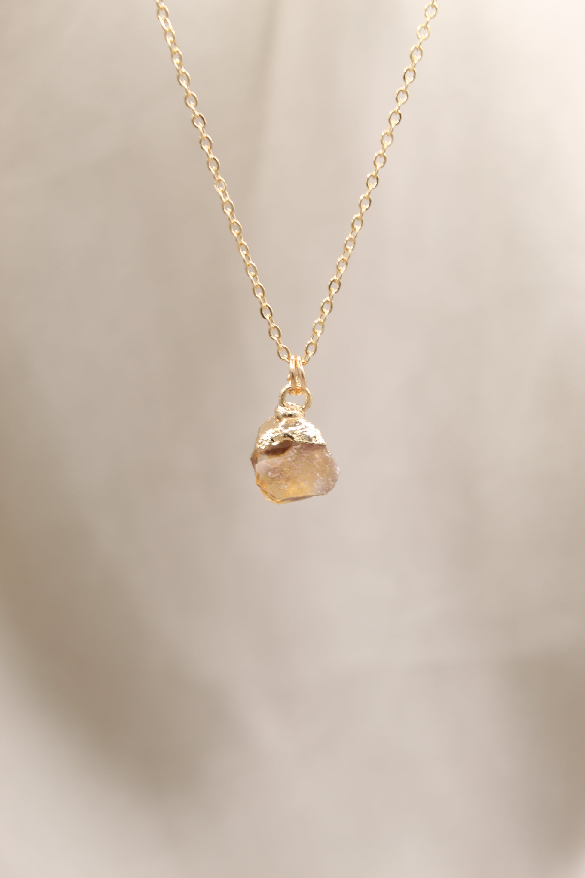 Gold necklace with a pendant on a beige background