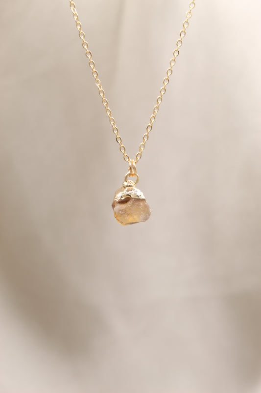 Gold necklace with a pendant on a beige background
