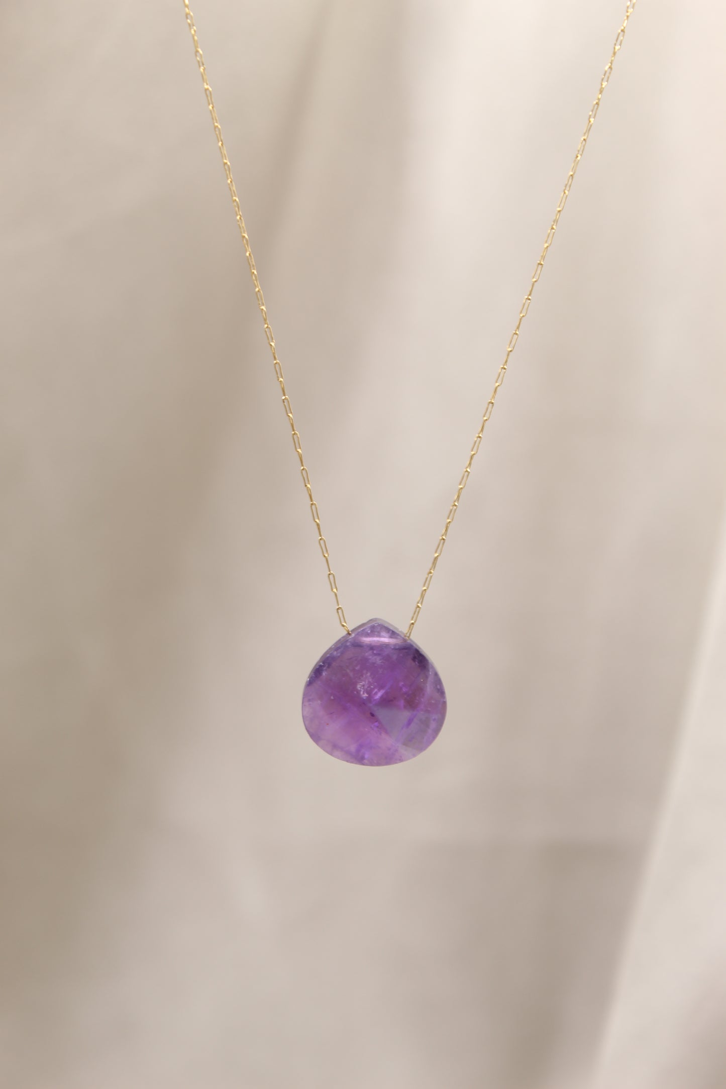 Purple gemstone necklace on a beige background