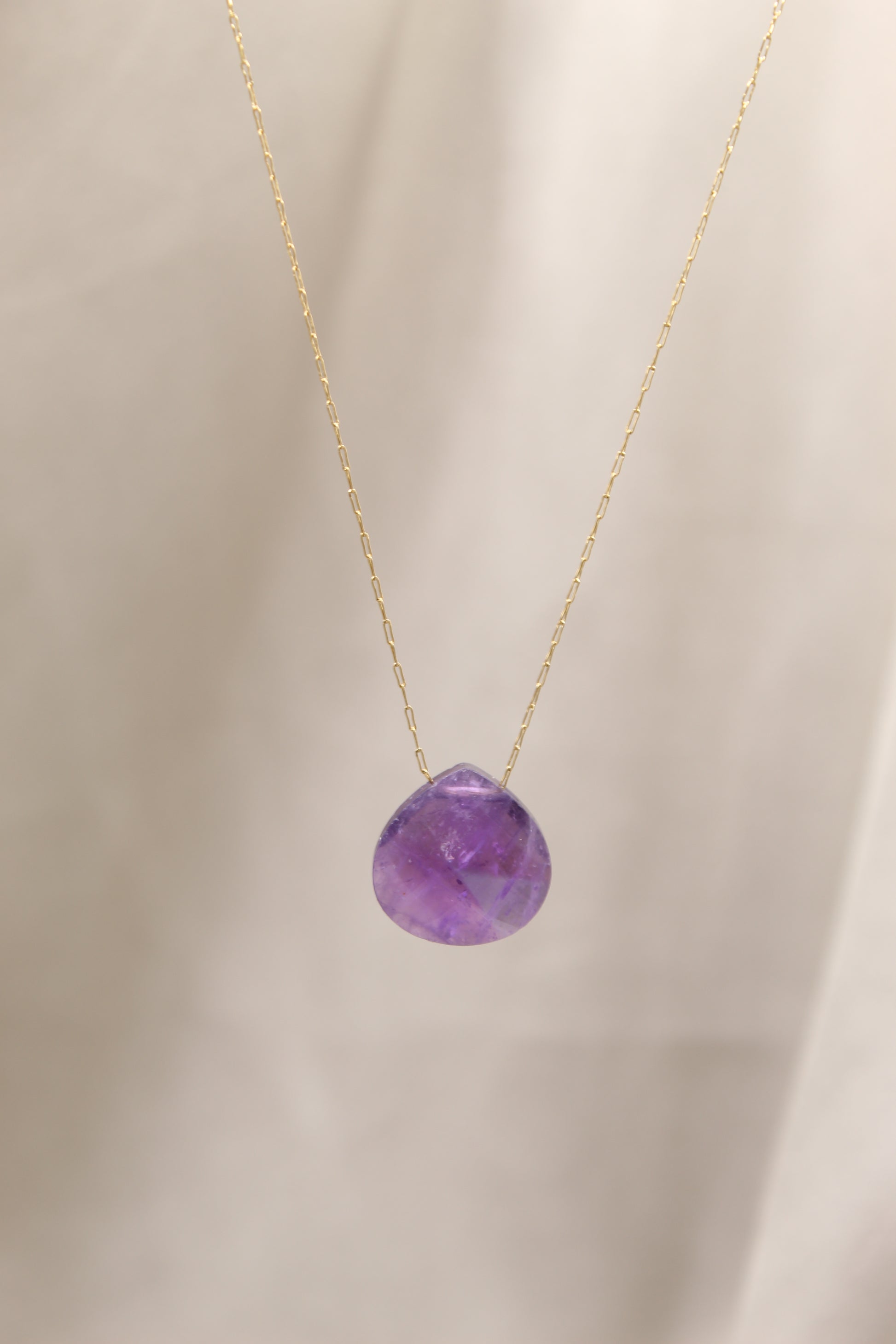 Purple gemstone necklace on a beige background