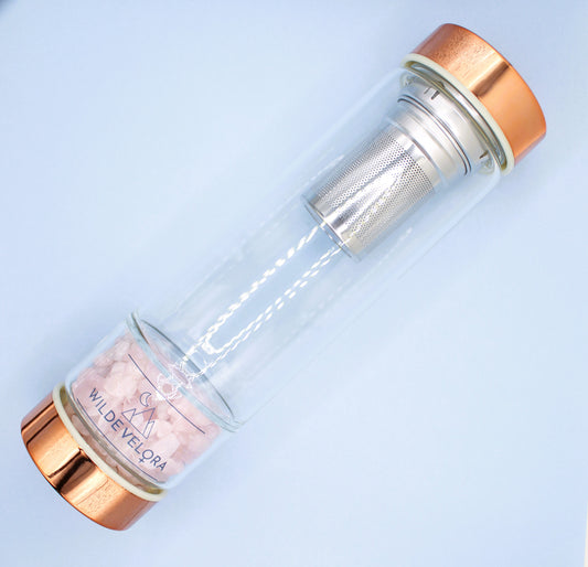 Clear glass bottle with rose gold cap and interior on a light blue background
