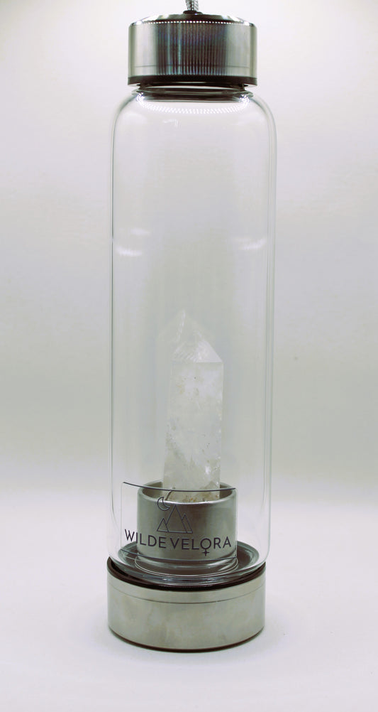 Clear glass bottle with metal cap and base on a white background