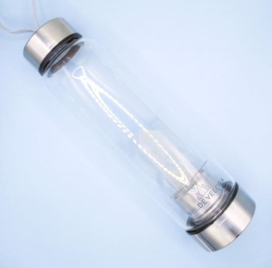 Clear bottle with metal cap and base on a light blue background
